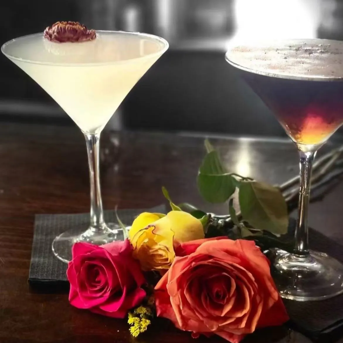 Two elegant martini cocktails decorated with fresh colorful roses